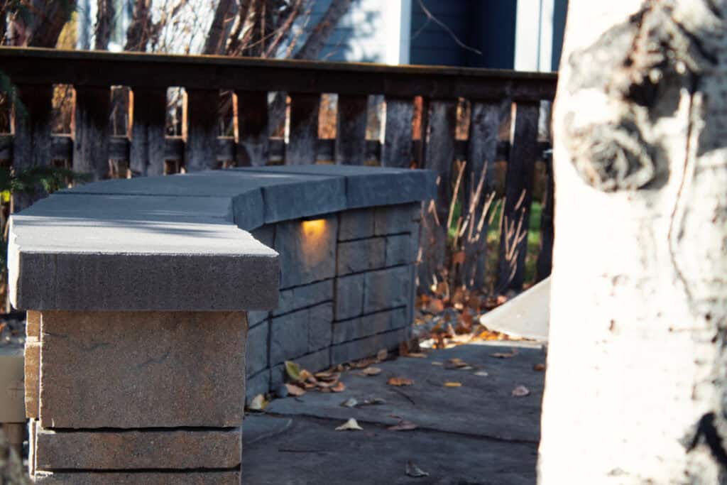 Natural stone seat wall with integrated cap lighting glowing at night in a Bozeman landscape